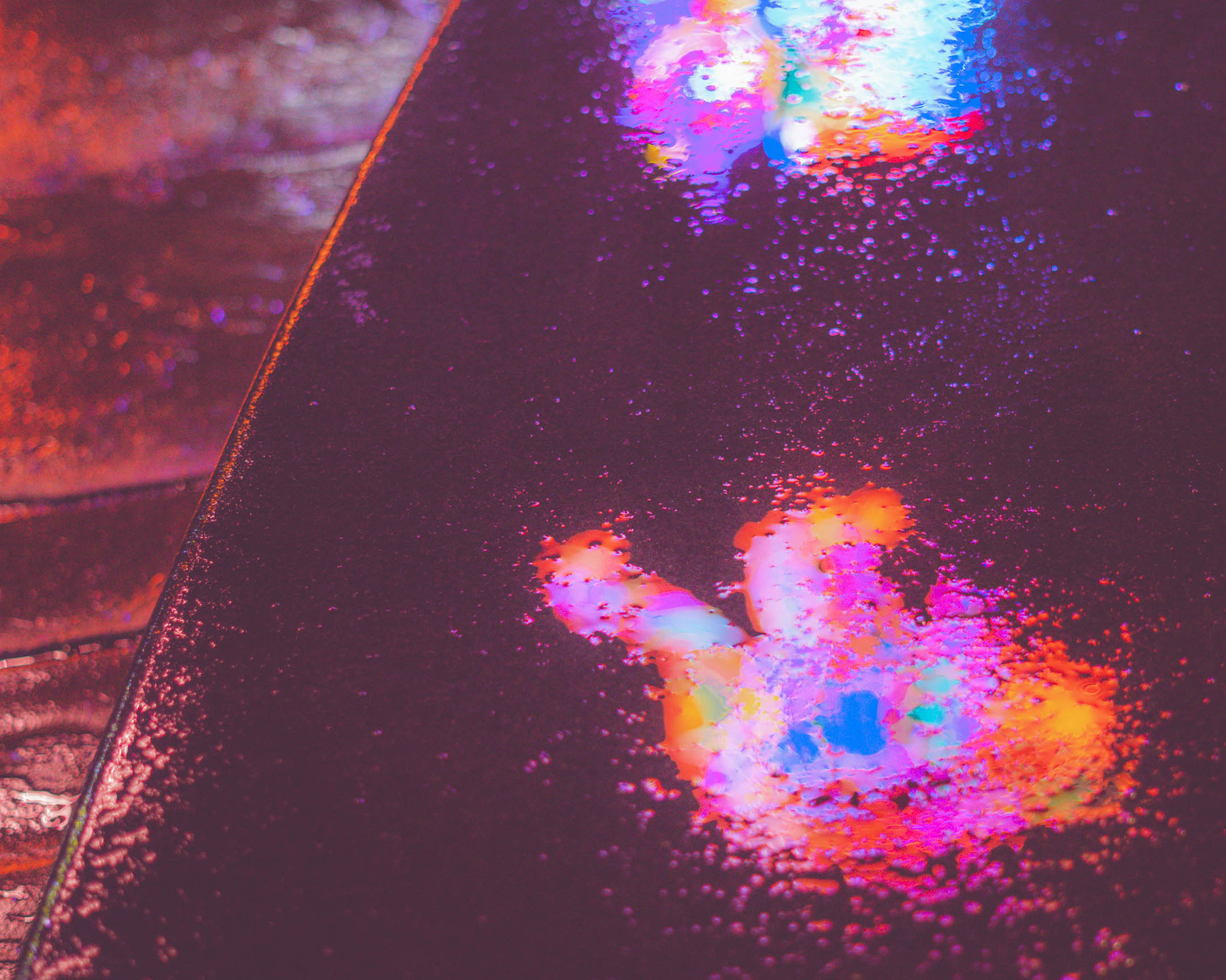 Photograph of a reflection of a monkey light display on a wet stone bench at Lumiere.